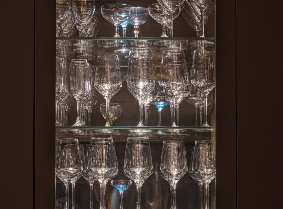 Gläser und Kristallgeschirr in einem beleuchteten Glasschrank, elegant und ansprechend.