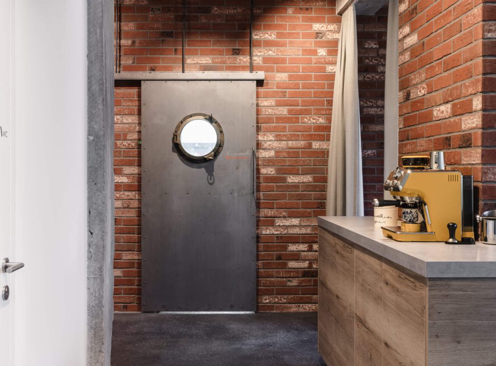 Moderne Küche mit Kaffeemaschine, Backsteinwand und kreativem Türdesign.