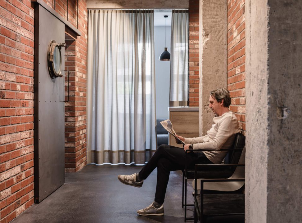 Modernes Interior mit Ziegelmauer, Vorhängen und Freizeitleser in stilvollem Raum.