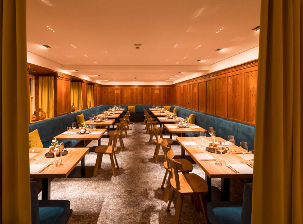 Elegante Restaurantbeleuchtung mit Holzwänden und stilvollen Tischen in warmem Ambiente.