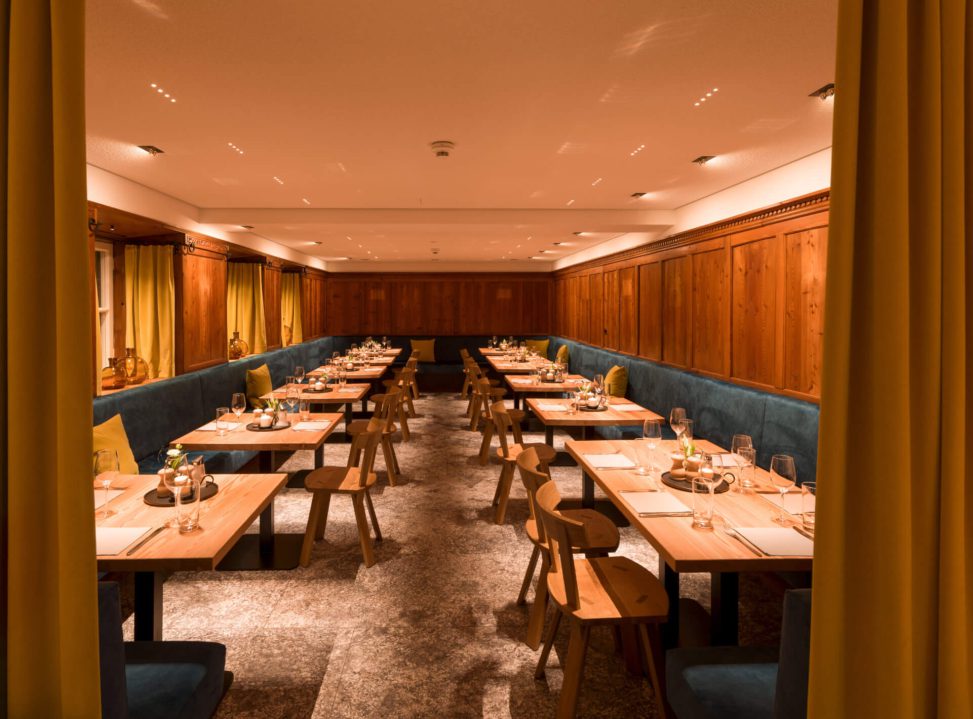 Elegant beleuchteter Restaurantbereich mit Holzwänden und modernem Mobiliar.