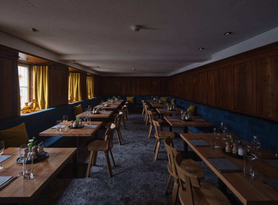 Einladendes Restaurant mit Holzstühlen, Tischen und gelben Vorhängen, stilvolle Beleuchtung.