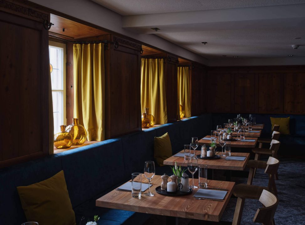 Elegante Tischdekoration in einem Restaurant mit warmem Licht und gelben Vorhängen.