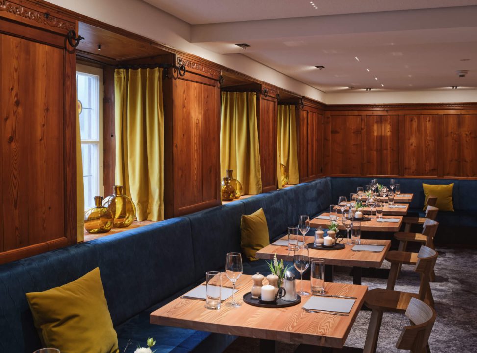 Elegante Innenbeleuchtung in einem stilvollen Raum mit Holzverkleidung und gemütlichen Tischen.