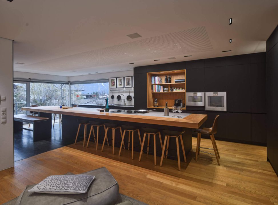 Moderne Küche mit Holzinsel, stylishen Stühlen und großflächigen Fenstern für optimale Beleuchtung.