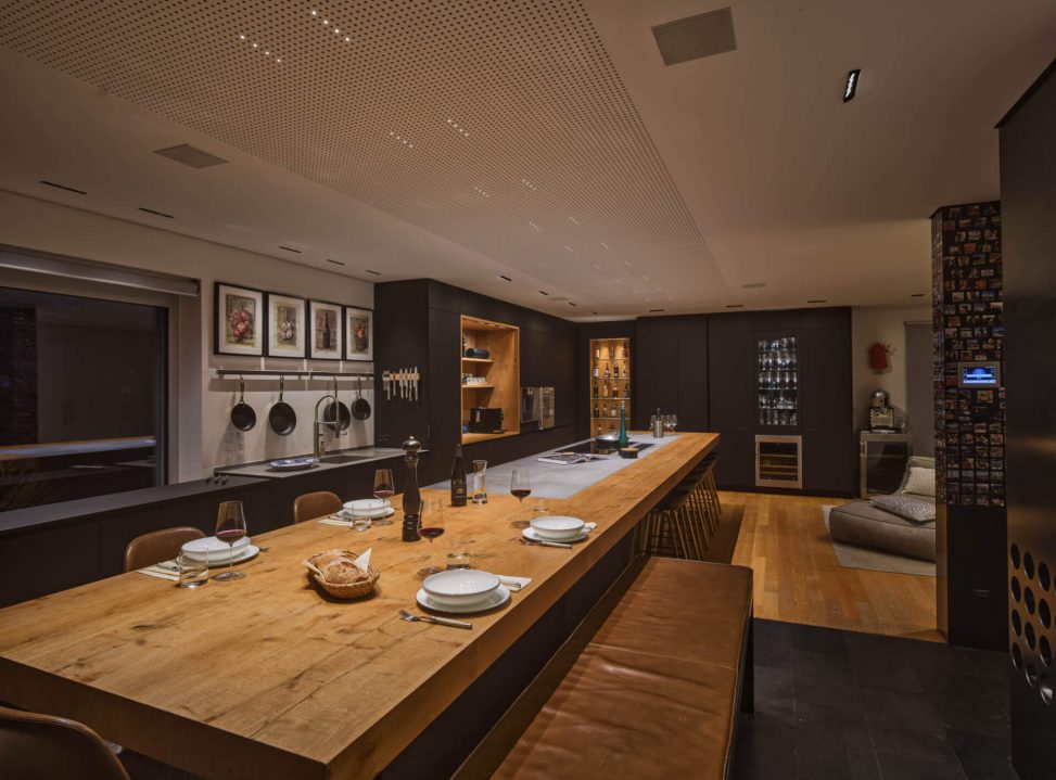 Moderne Küche mit stilvoller Holzinsel, Kunstwerken und innovativer Beleuchtung.