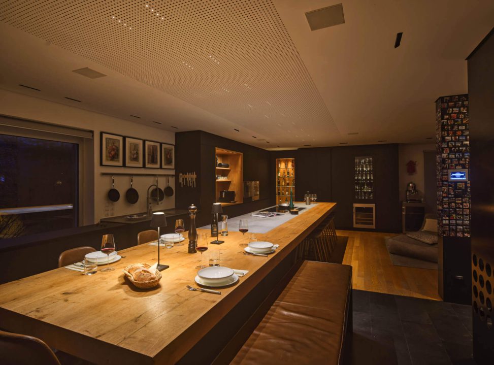 Stilvolle Küche mit Holz-Esstisch, funktionaler Beleuchtung und modernem Design.