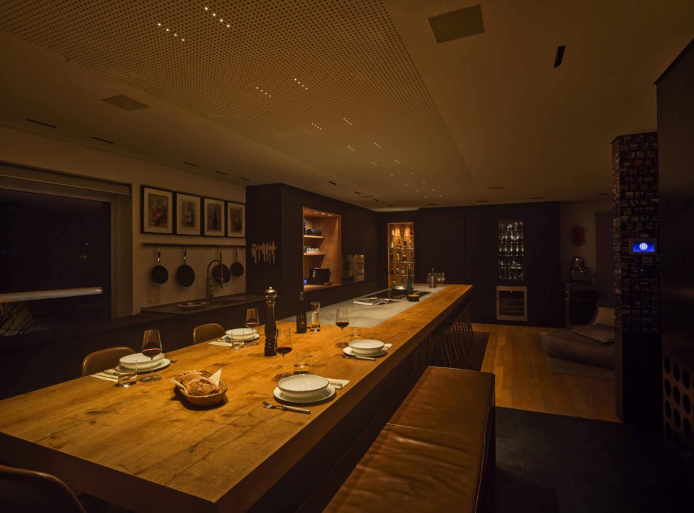 Moderne Küche mit stilvollem Lichtdesign, Holz-Tisch und eleganten Stühlen.