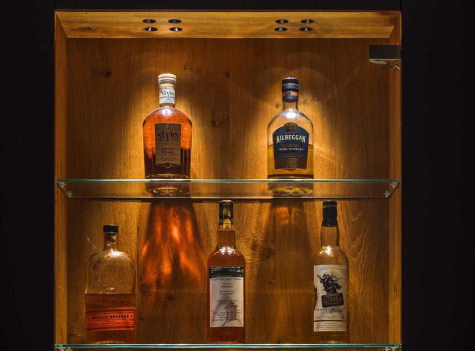 Elegante Spirituosenregale mit warmem Licht, das die Flaschen stilvoll in Szene setzt.