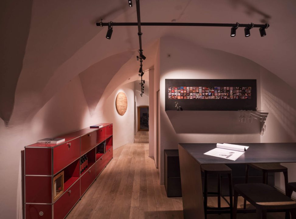 Modernes Lichtdesign in einem stilvollen, offenen Raum mit rotem Möbelstück und Holzfußboden.