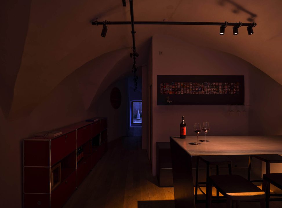 Moderne Küche mit stimmungsvoller Beleuchtung, Weinglas und dekorativem Kunstwerk an der Wand.